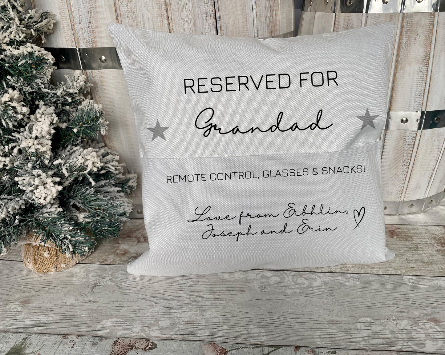Custom grey cushion with printed text ‘Reserved for Grandad’, pocket labelled for remote control, glasses and snacks, and personalised message ‘Love from EibhlÃn, Joseph and Erin’