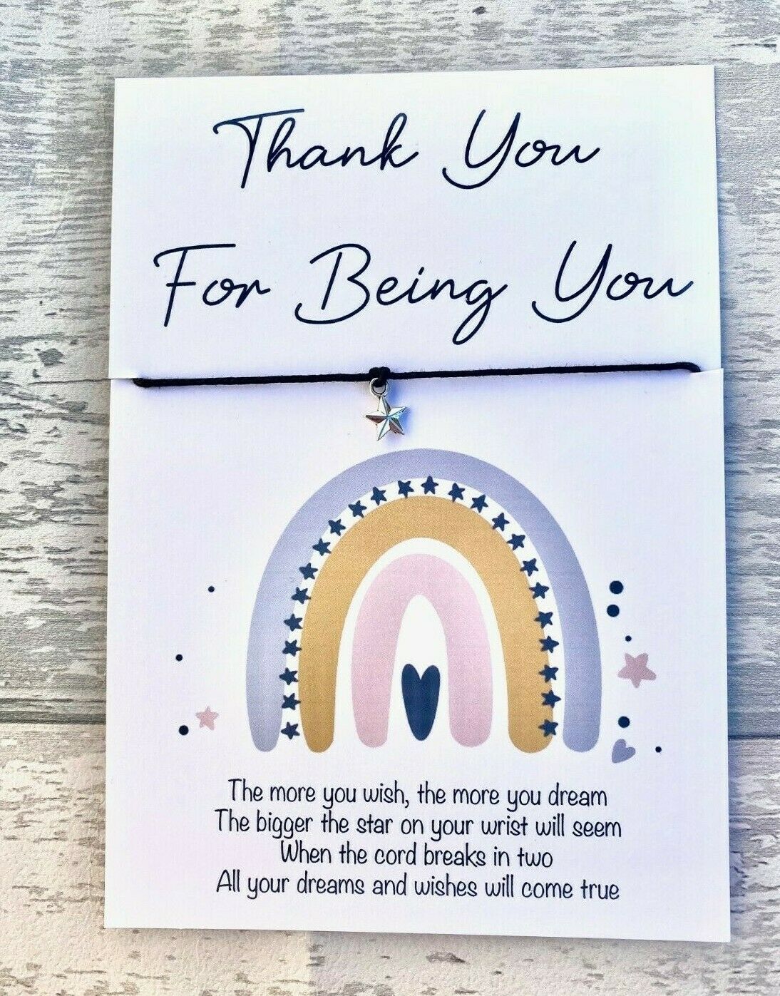 Card with rainbow design and bracelet on a wooden surface