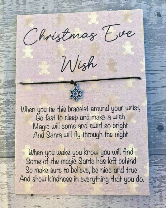 Bracelet with snowflake charm on a Christmas Eve wish card against a wooden background