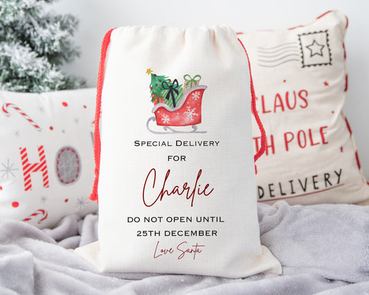 Unique personalised Christmas gift sack with red sleigh and presents – “Special Delivery for Charlie – Do Not Open Until 25th December – Love Santa” – custom festive Santa sack gift