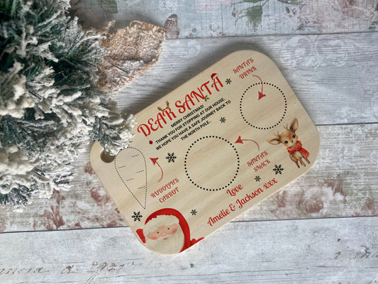 Custom Christmas Eve treat board for Santa, made of wood and featuring designated spots for a drink, snack, and Rudolph's carrot. Includes festive images of Santa and a reindeer with personalised names for a magical holiday touch.