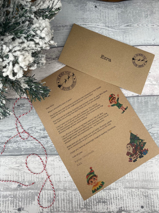 A personalised letter from Father Christmas with a kraft envelope and red and white string, displayed on a wooden surface with Christmas decorations.