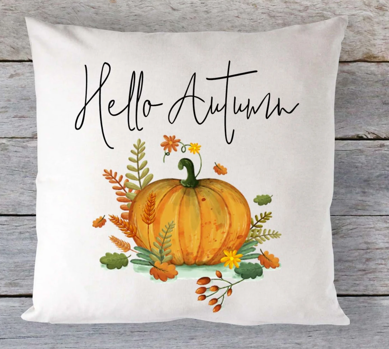 A square-shaped cushion with an autumn theme, displaying a pumpkin and the text 'Hello Autumn' on a wooden background.