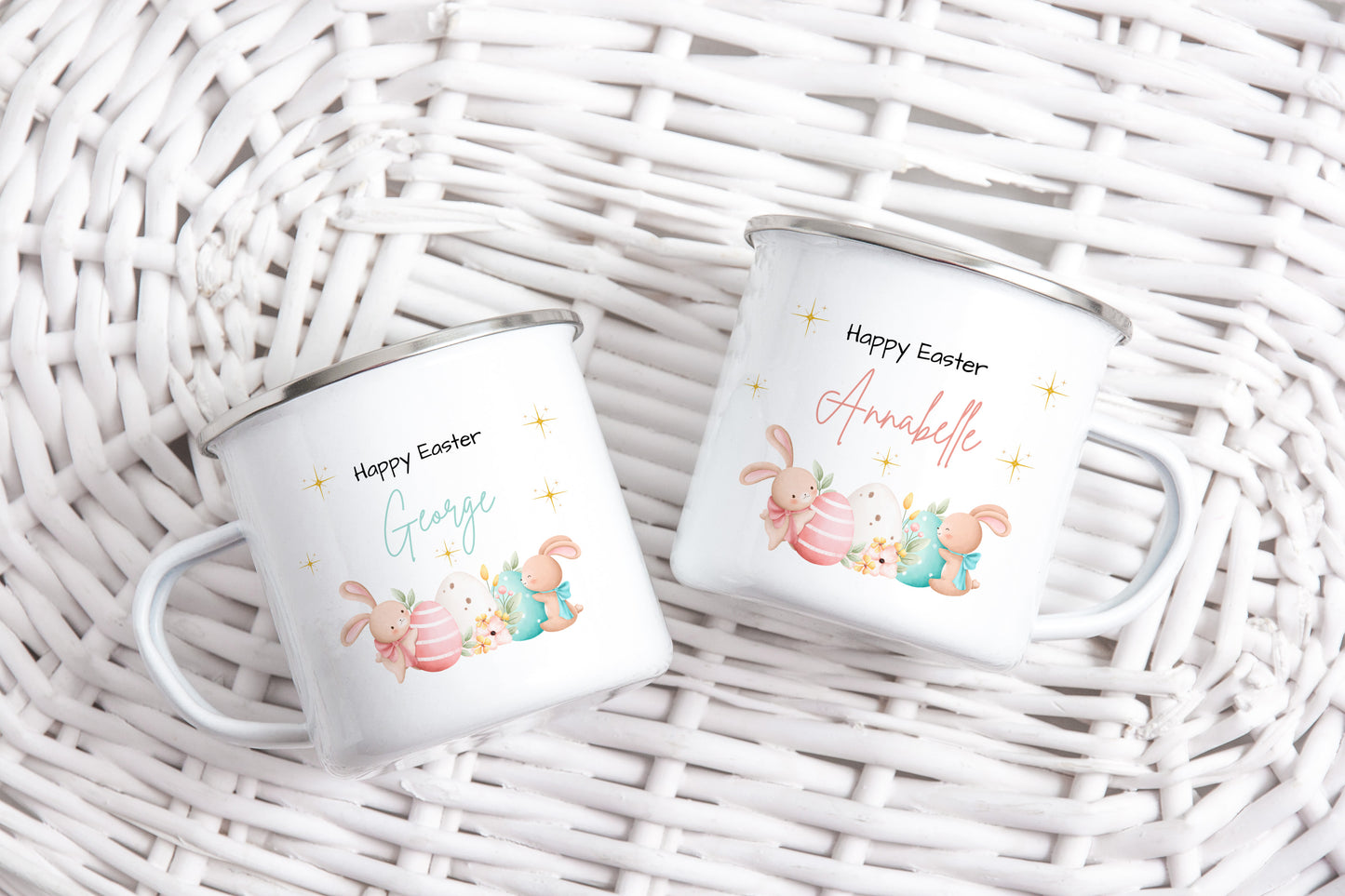 Custom enamel Easter mugs featuring bunny and egg illustrations with names āGeorgeā and āAnnabelle,ā displayed on a white wicker background.