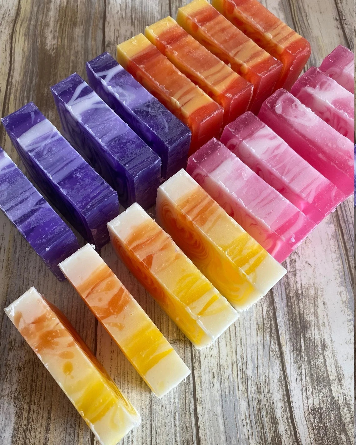 An assortment of colorful handmade soap bars arranged in a pattern on a wooden surface.