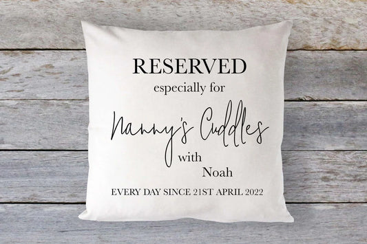 A square-shaped cushion with a linen cover, featuring personalised text that reserves it 'especially for Nanny's Cuddles' with a name and date.