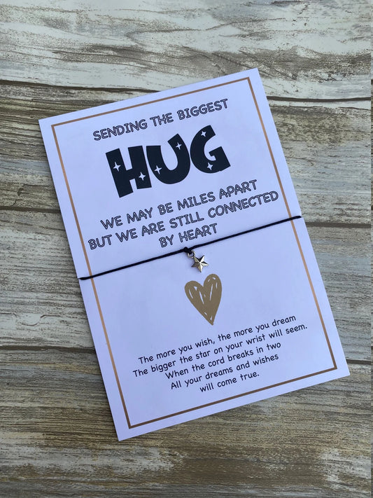 A packaged 'Sending A Hug' wish bracelet with a silver-plated Tibetan charm in the shape of a heart, presented on an A6 card with a clear cellophane pouch.