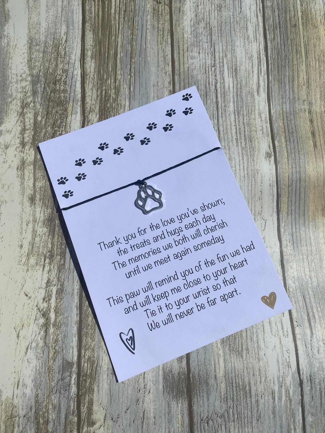 A sympathy card with a bracelet made of waxed cotton cord and a Tibetan Silver Plated Charm, displayed on a wooden background.