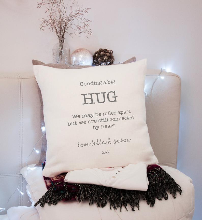A personalized cushion with the text 'Sending a big HUG' printed on it, placed on a chair with a decorative setting in the background.