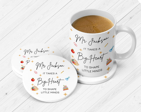 White ceramic mug and coasters set featuring the text “Mr Jackson – It takes a big heart to shape little minds.” Decorated with school-themed illustrations like an apple, scissors, paint palette, cake, and pencil. Displayed on a light wooden surface.