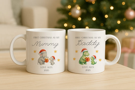Two Christmas-themed mugs with elephant and dinosaur illustrations in front of a decorated Christmas tree.