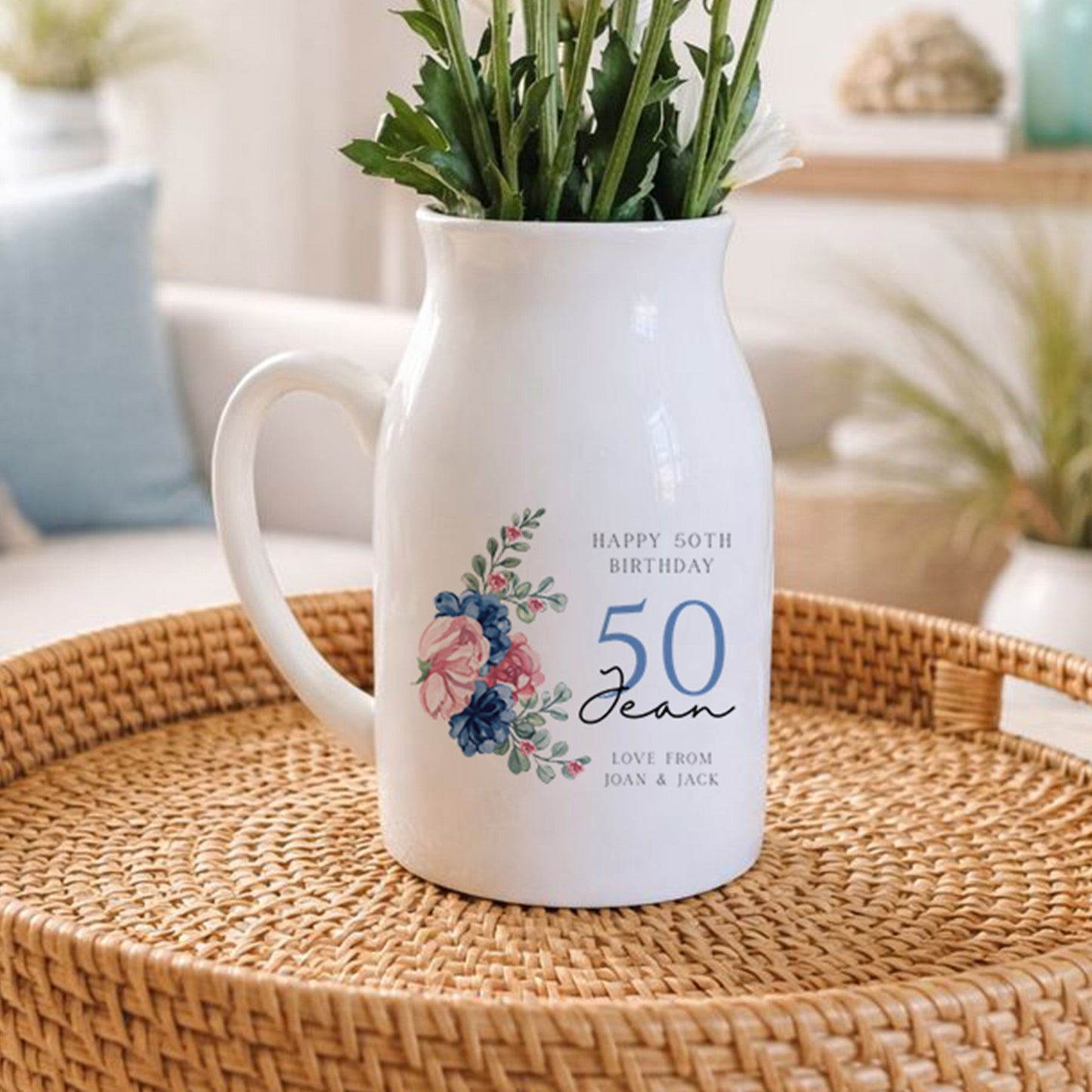 White pitcher with floral design on a woven tray in a living room setting