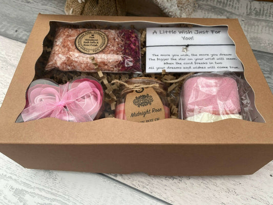 Gift set with bath bombs and a candle in a cardboard box on a wooden surface.
