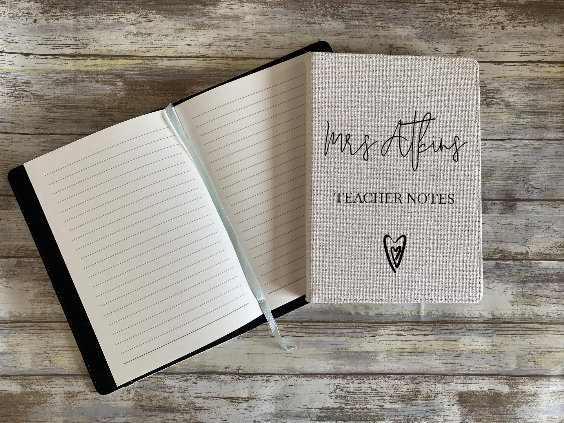 Open notebook with 'Mrs. Atkins Teacher Notes' on a wooden surface