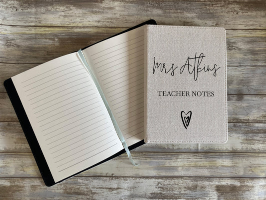 Open notebook with 'Mrs. Atkins Teacher Notes' on a wooden surface