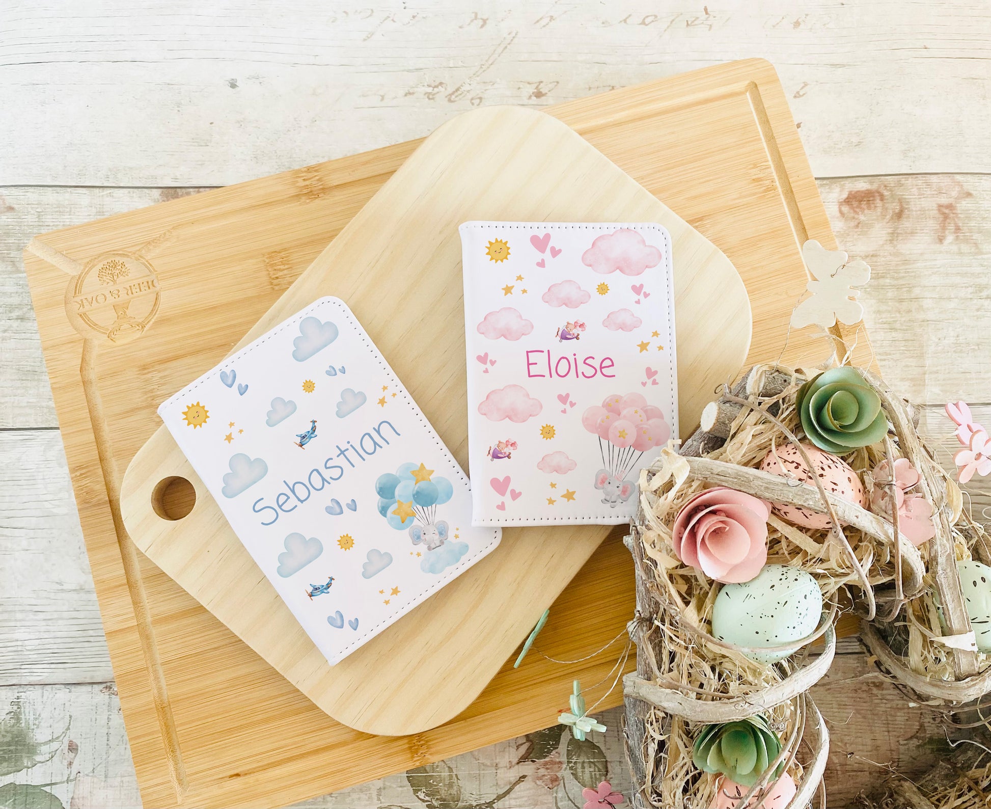 Personalised children's passport holders in pink and blue designs with clouds, hearts, balloons, and custom names, for girls and boys