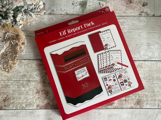 A festive Elf Report Pack displayed on a rustic wooden surface with a snow-dusted tree in the corner. The shows illustrated contents: elf report cards, mini envelopes, a red pencil, and two sticker sheets featuring playful Christmas characters and icons. Designed in cheerful red, white, and green tones, it’s a fun and interactive Christmas activity set for kids to report elf behavior in the lead-up to Christmas Day
