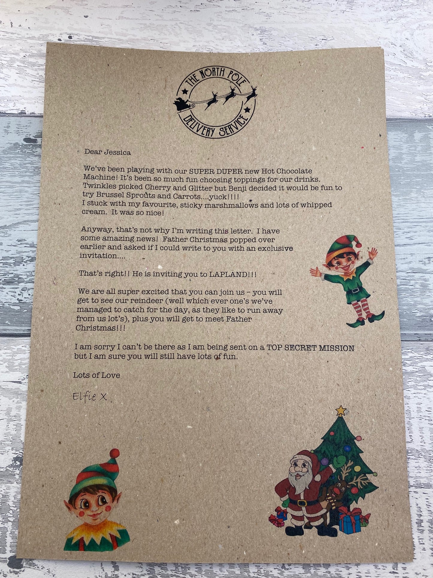 Letter from Santa Claus on kraft paper with Christmas-themed illustrations on a wooden surface.