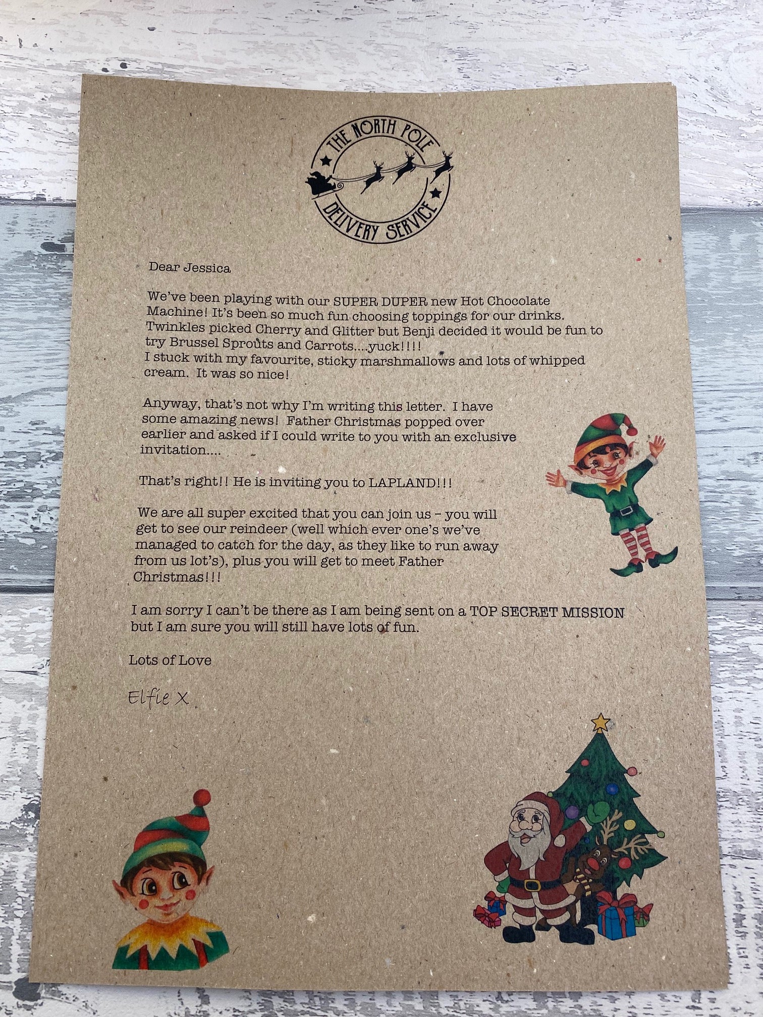 Letter from Santa Claus on kraft paper with Christmas-themed illustrations on a wooden surface.