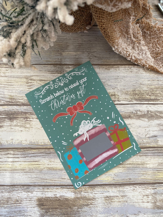 Holiday-themed scratch card with presents and a bow on a wooden surface