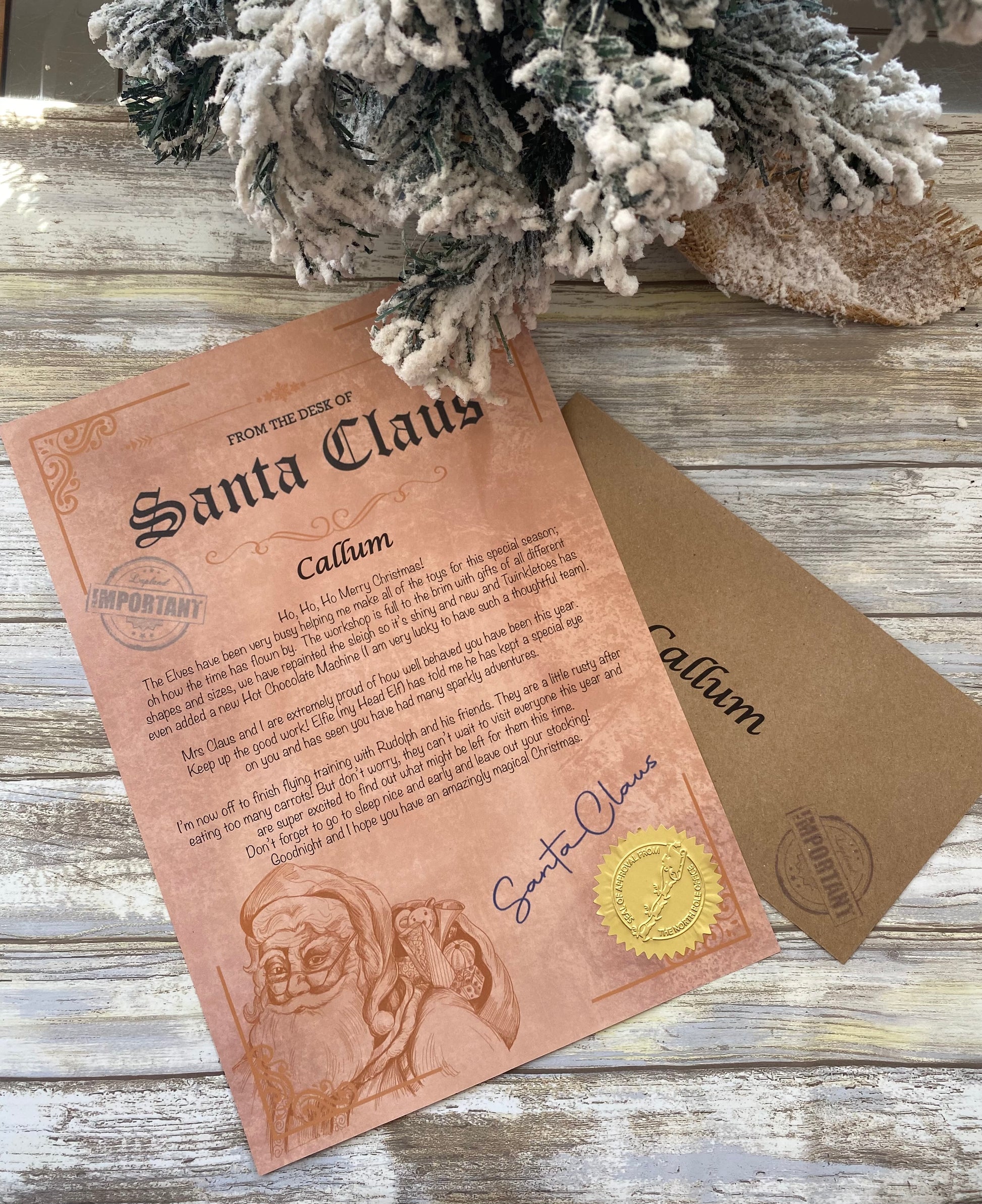 Letter from Santa Claus on a rustic wooden surface with a flocked Christmas tree branch.