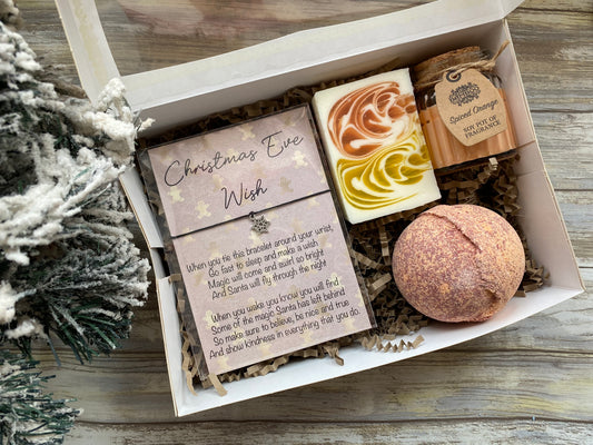 Gift set with bath bomb, soap, and card on a wooden surface with Christmas decorations.