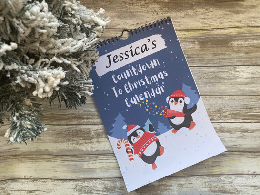 Personalised Christmas countdown calendar with penguin design on a wooden surface.