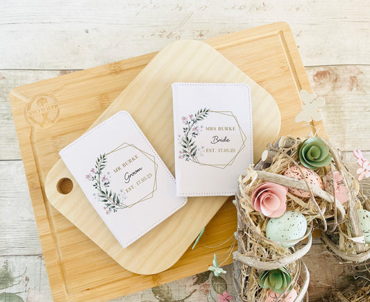 Set of personalised white passport covers for bride and groom with floral design and custom names, ideal wedding or honeymoon gift