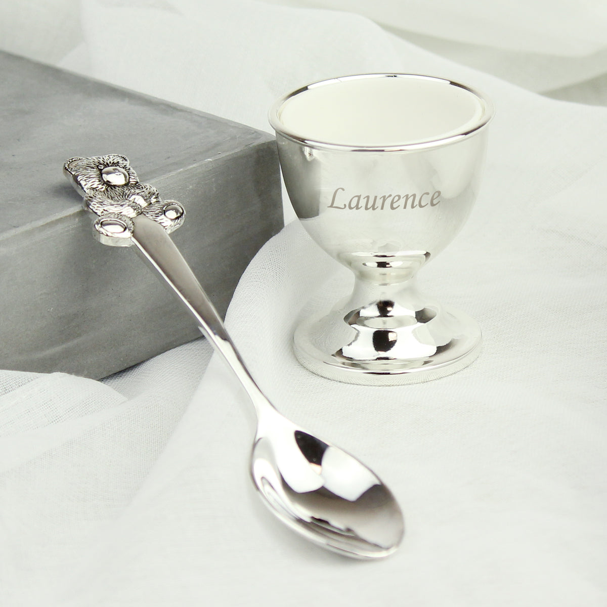 Personalised Silver egg cup and spoon set with 'Laurence' engraving on a white background