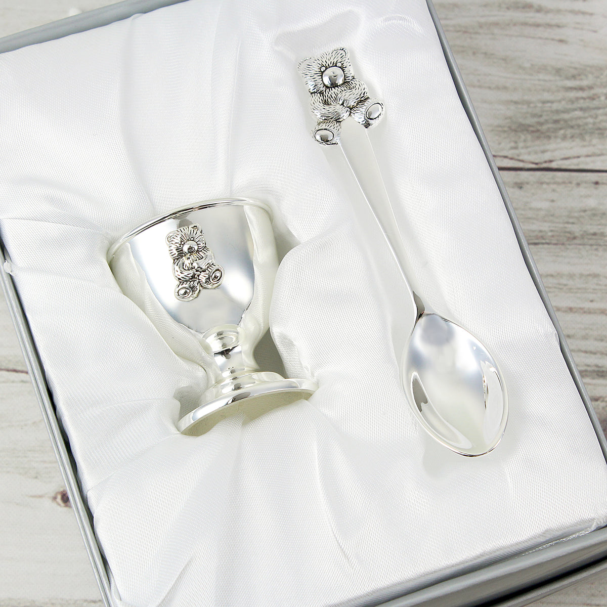 Personalised Silver egg cup and spoon set with decorative elements in a box on a wooden surface