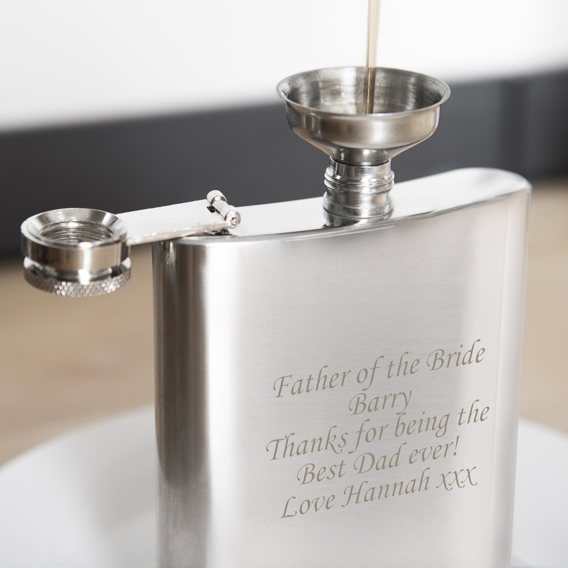 Stainless steel hip flask with engraved message on a white surface