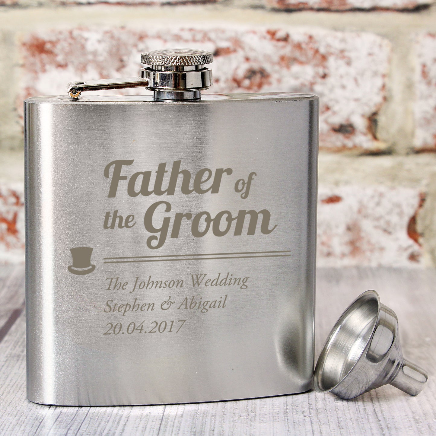 Stainless steel flask engraved with 'Father of the Groom' and wedding details on a textured surface.