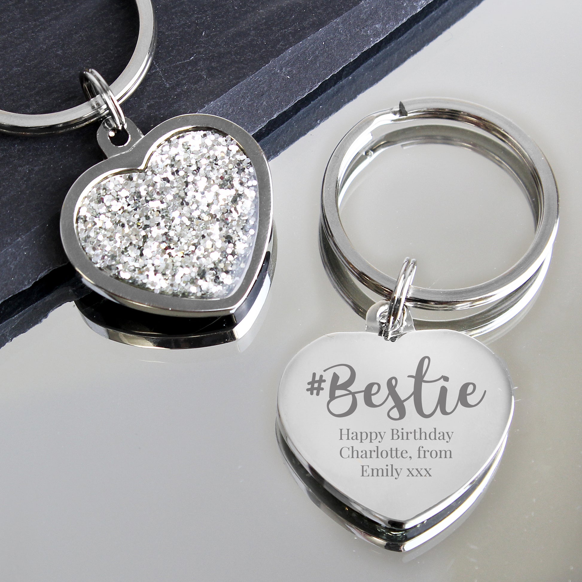 Two heart-shaped keychains, one with glittery surface and '#Bestie' engraving on a reflective surface.