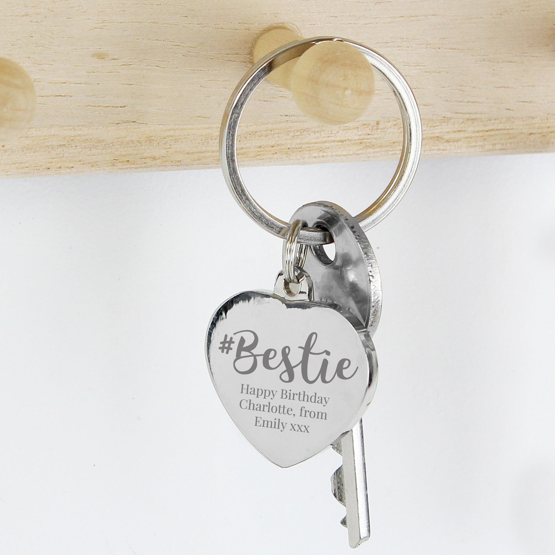 Silver keychain with heart-shaped tag and engraved message on a light wooden background