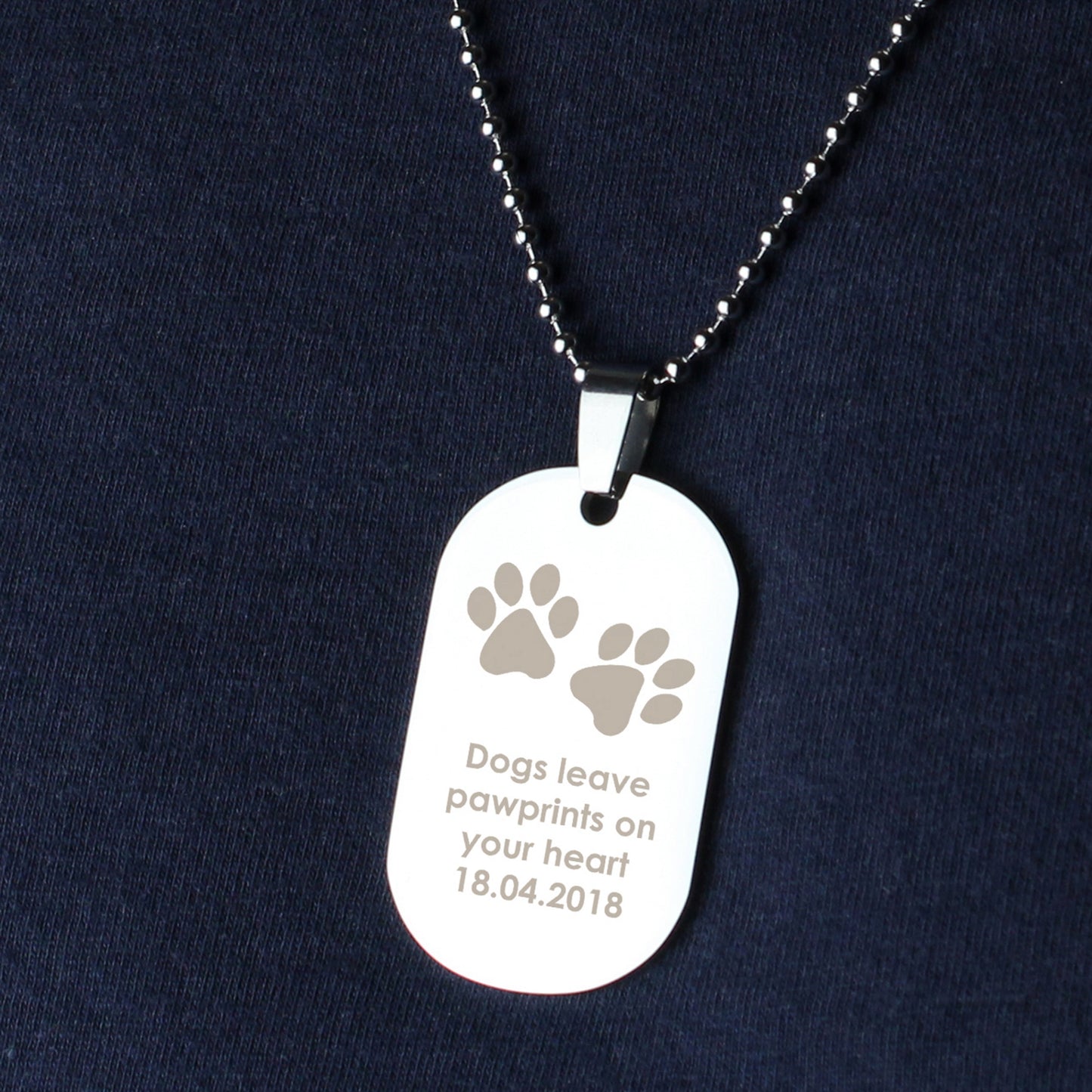 Dog tag necklace with paw prints and text on a dark blue background