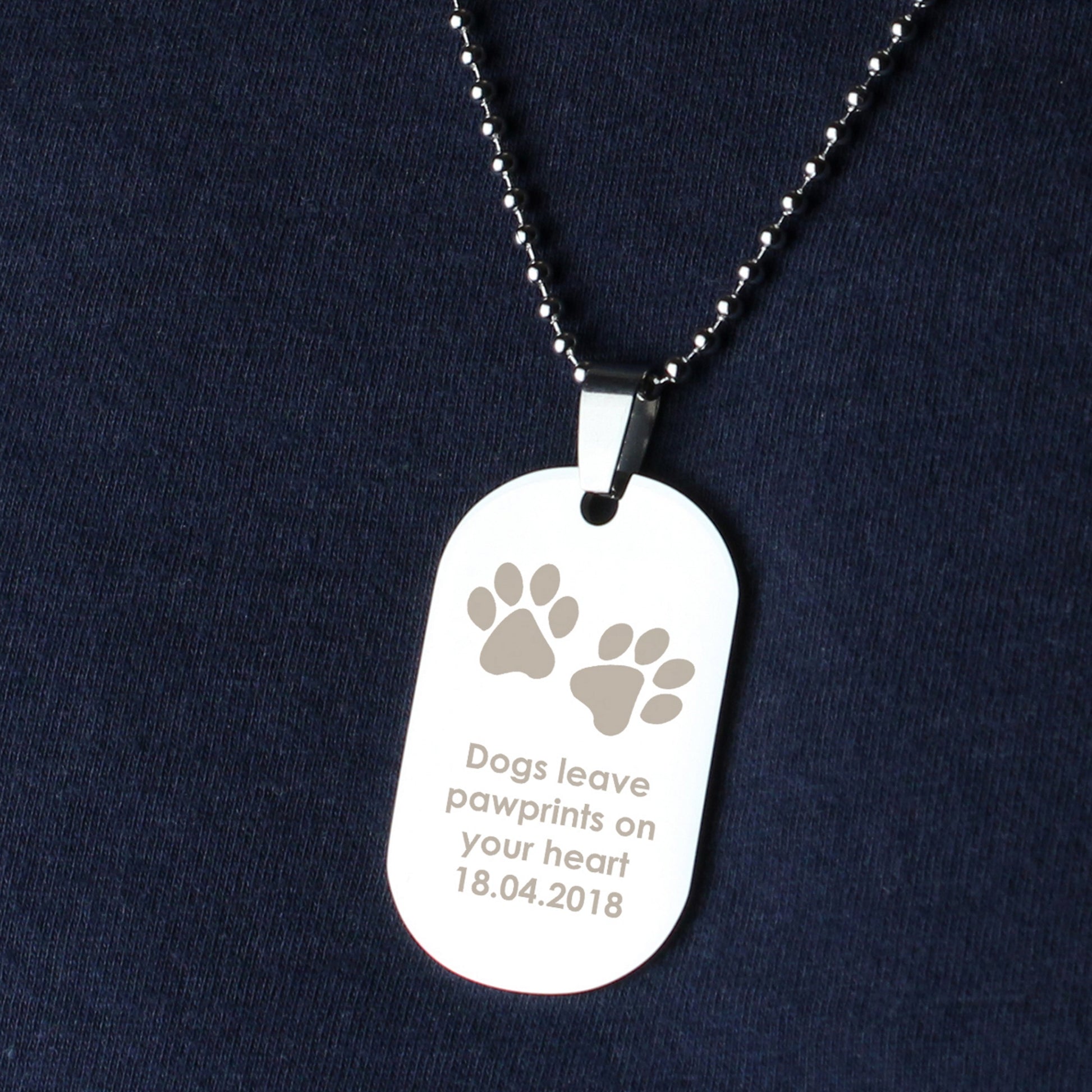 Dog tag necklace with paw prints and text on a dark blue background