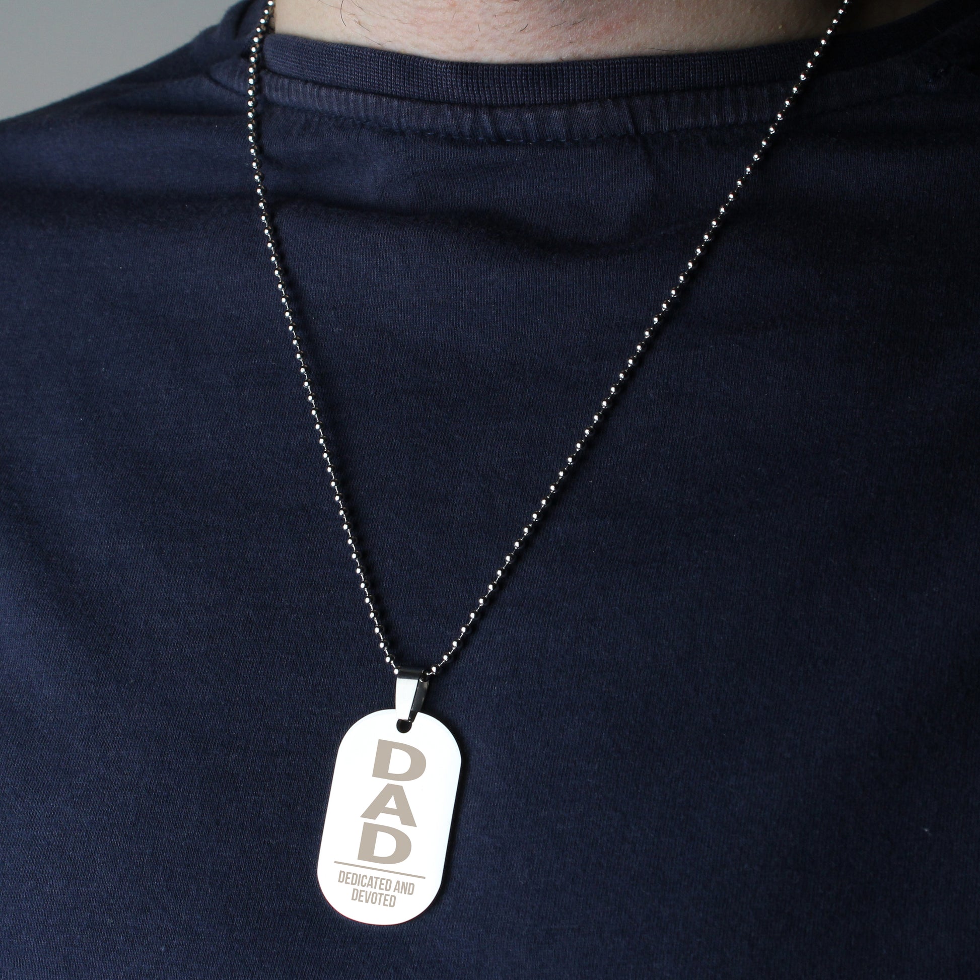 Necklace with a 'DAD' dog tag on a dark shirt