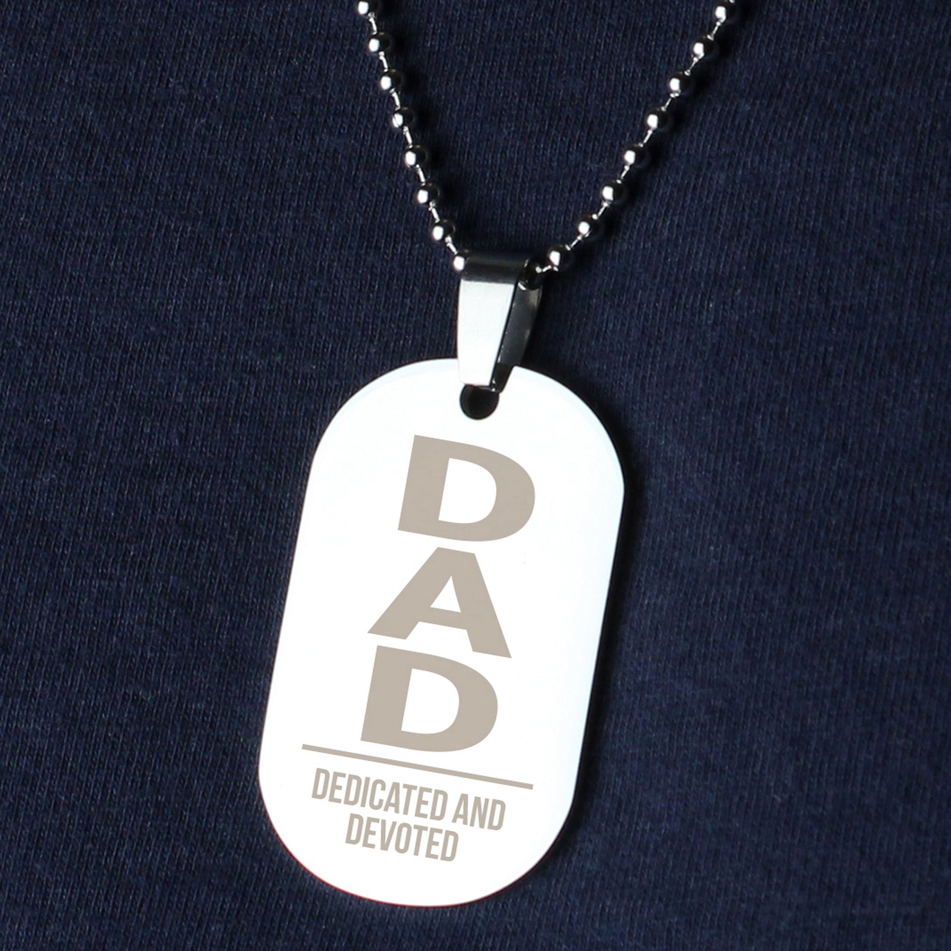 Dog tag necklace with 'DAD Dedicated and Devoted' text on a dark blue background