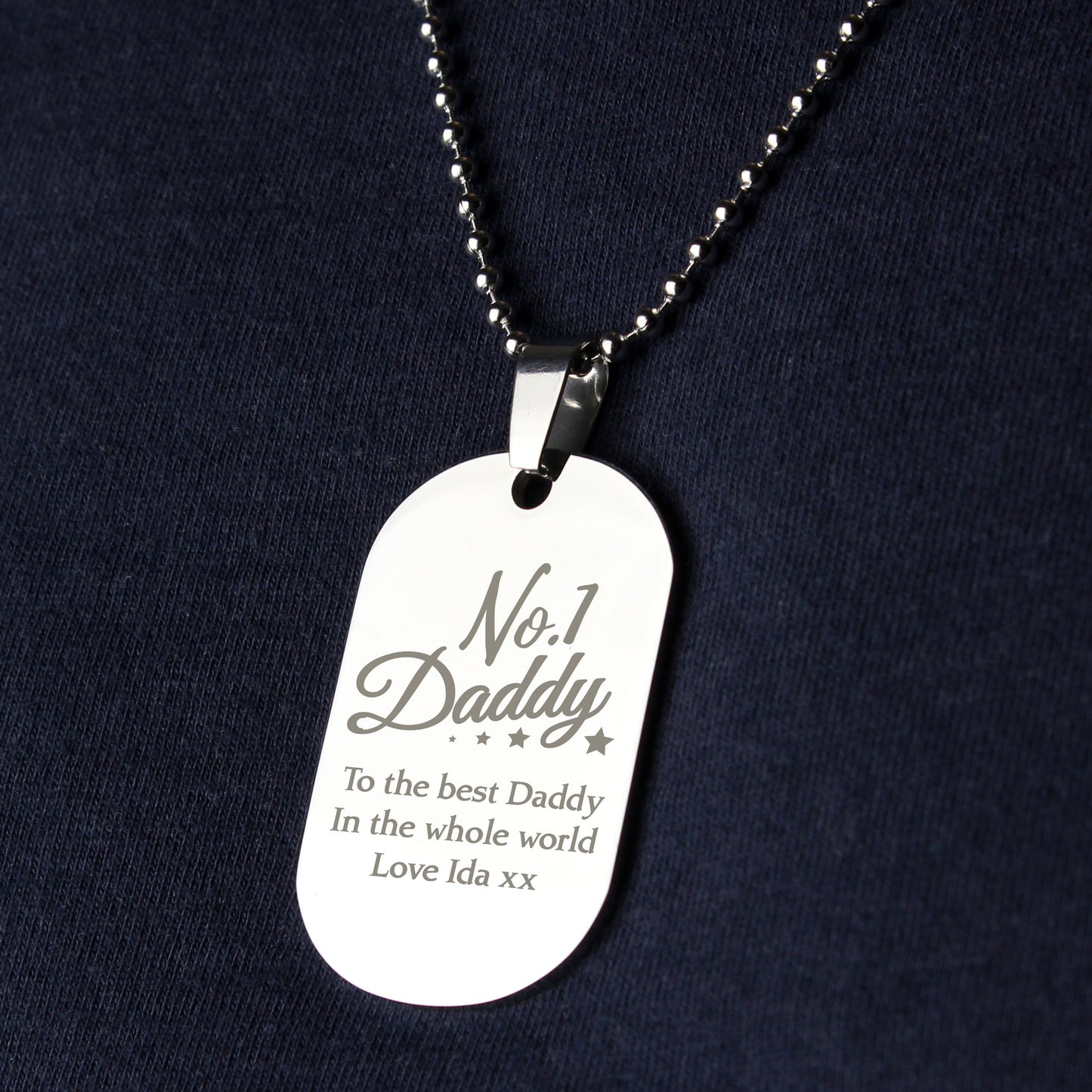 Silver dog tag necklace with engraved text on a dark background