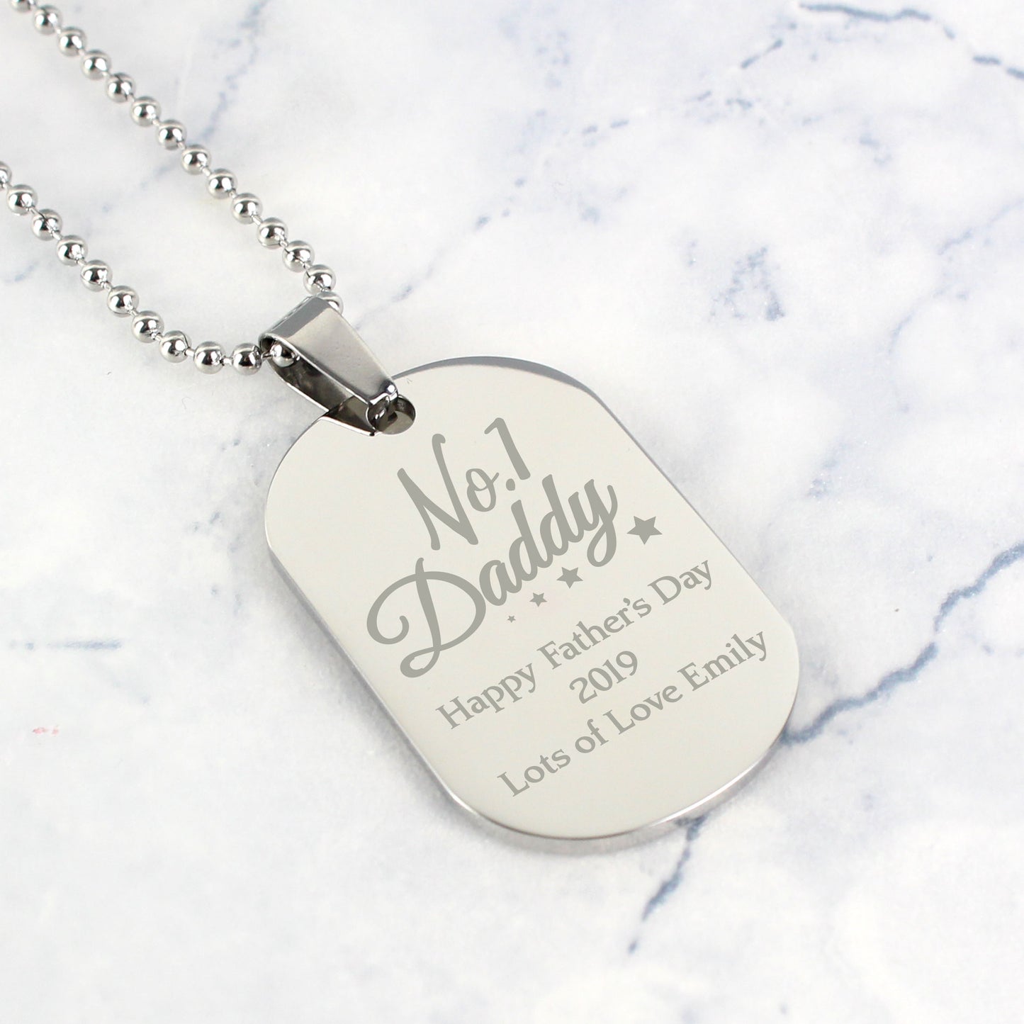 Personalised Dog tag necklace with engraved text on a marble background