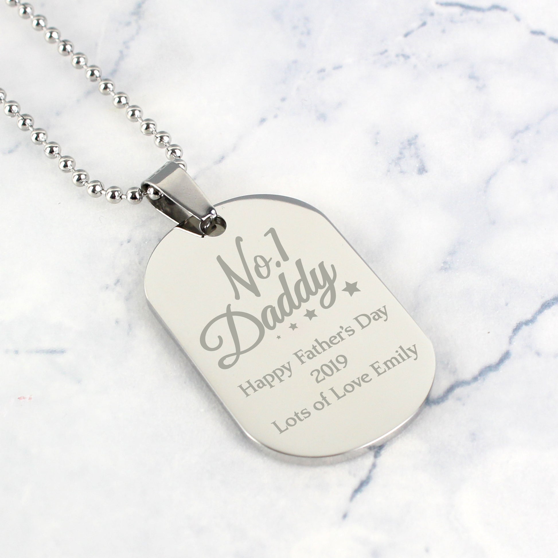 Personalised Dog tag necklace with engraved text on a marble background