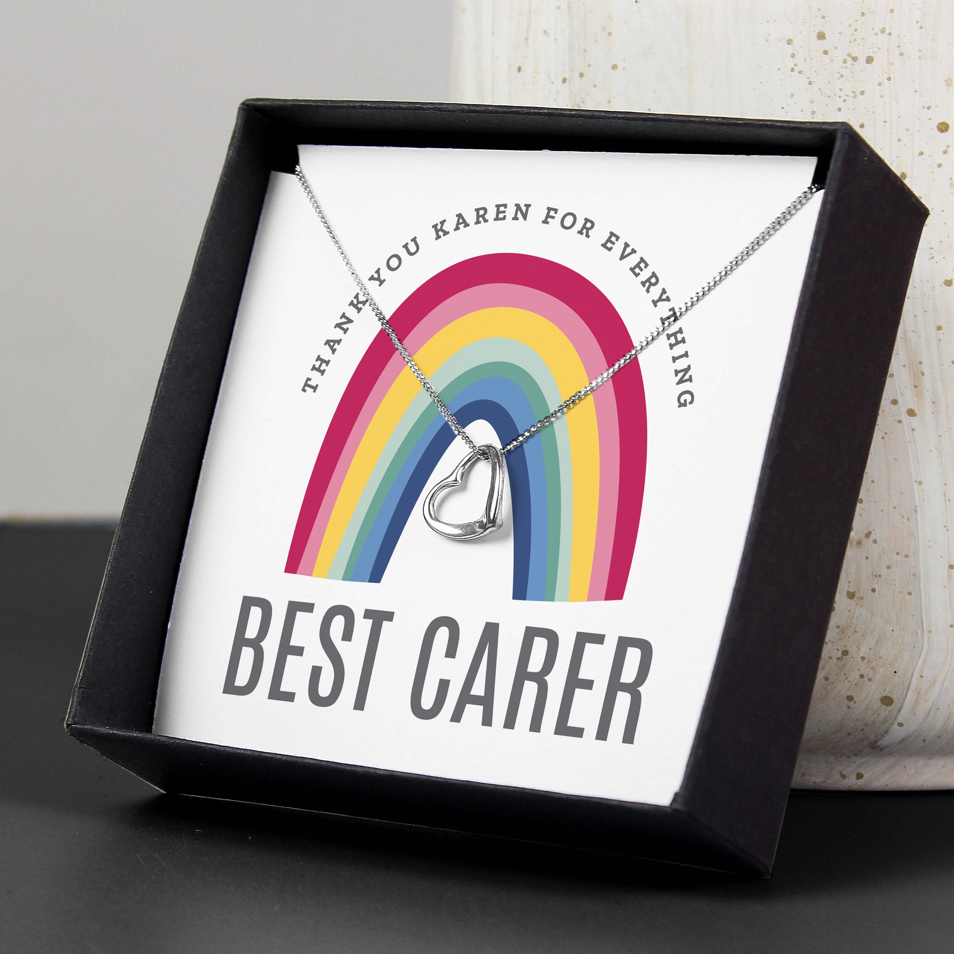 Necklace with heart pendant in a box with a rainbow design and text.