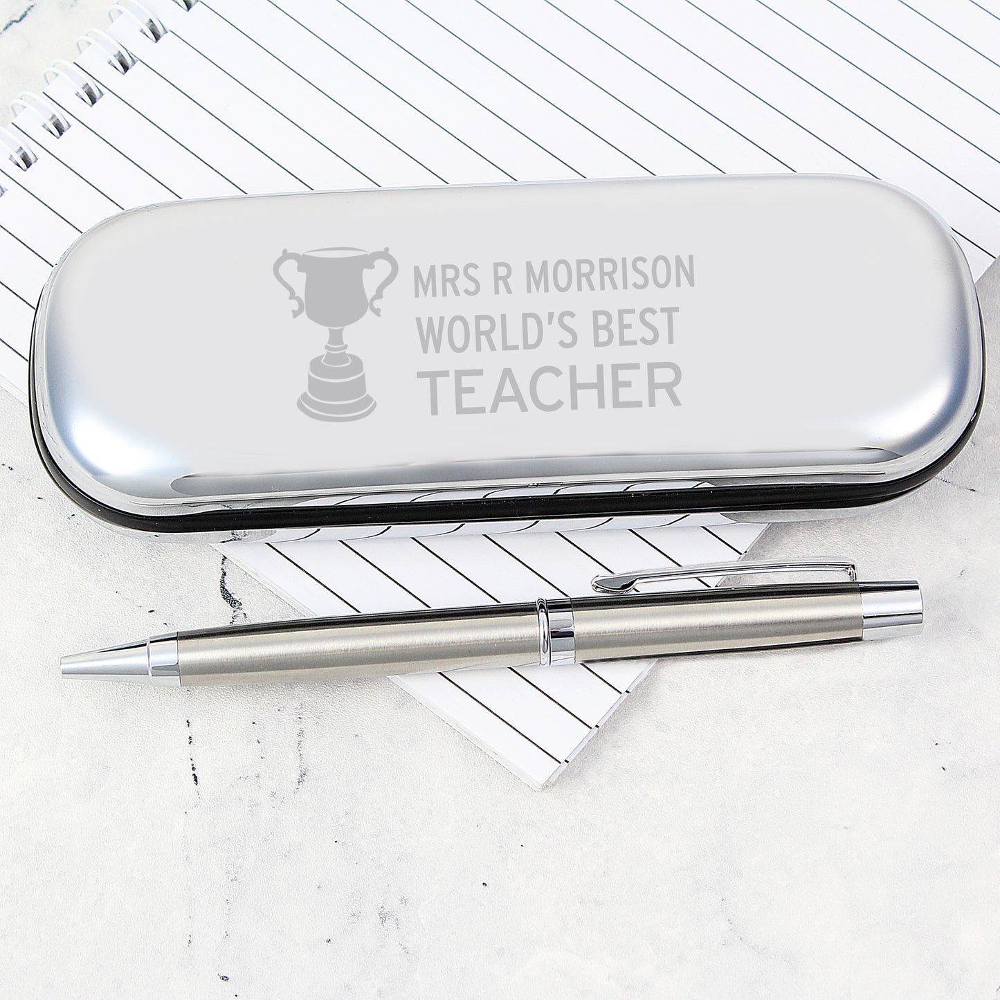 Silver pen case with engraved text on a white background