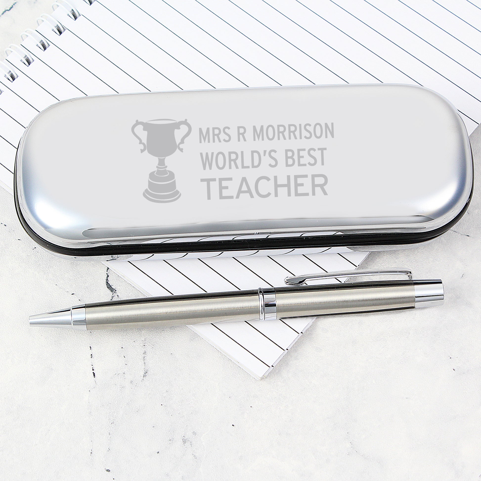 Silver pen case with engraved text on a white background