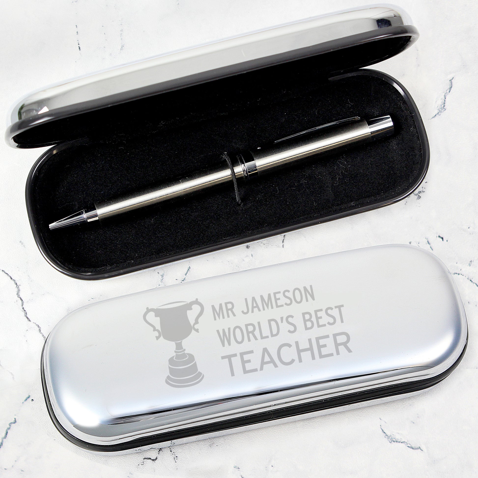 Silver pen in a case with 'Mr Jameson World's Best Teacher' engraving on a white background