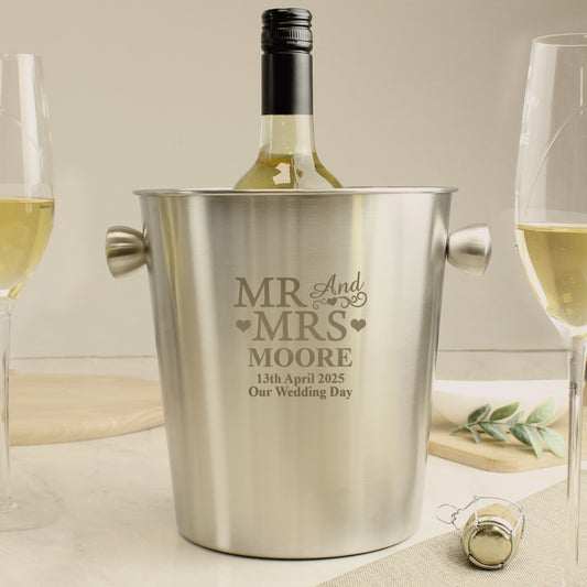 Personalised wine cooler with engraved text, bottle of white wine, and glasses on a table.