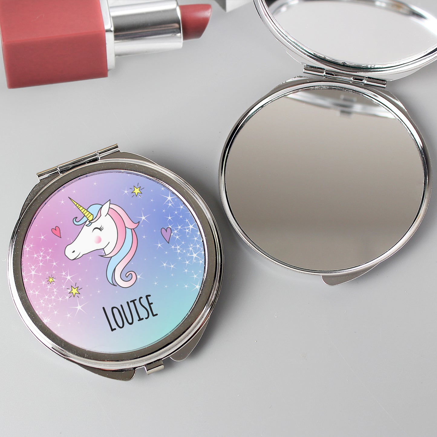 Compact mirror with unicorn design and 'LOUISE' text on a light gray background