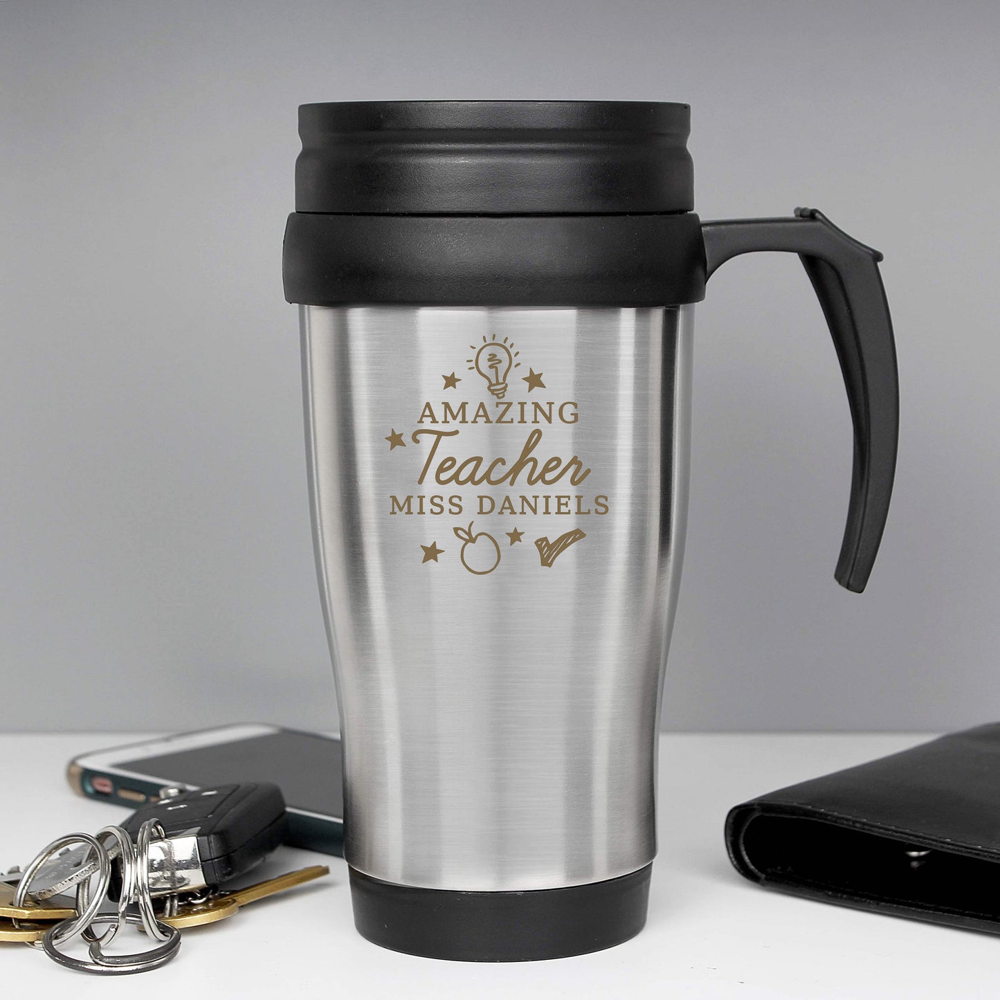 Stainless steel travel mug with 'Amazing Teacher Miss Daniels' engraving on a grey background