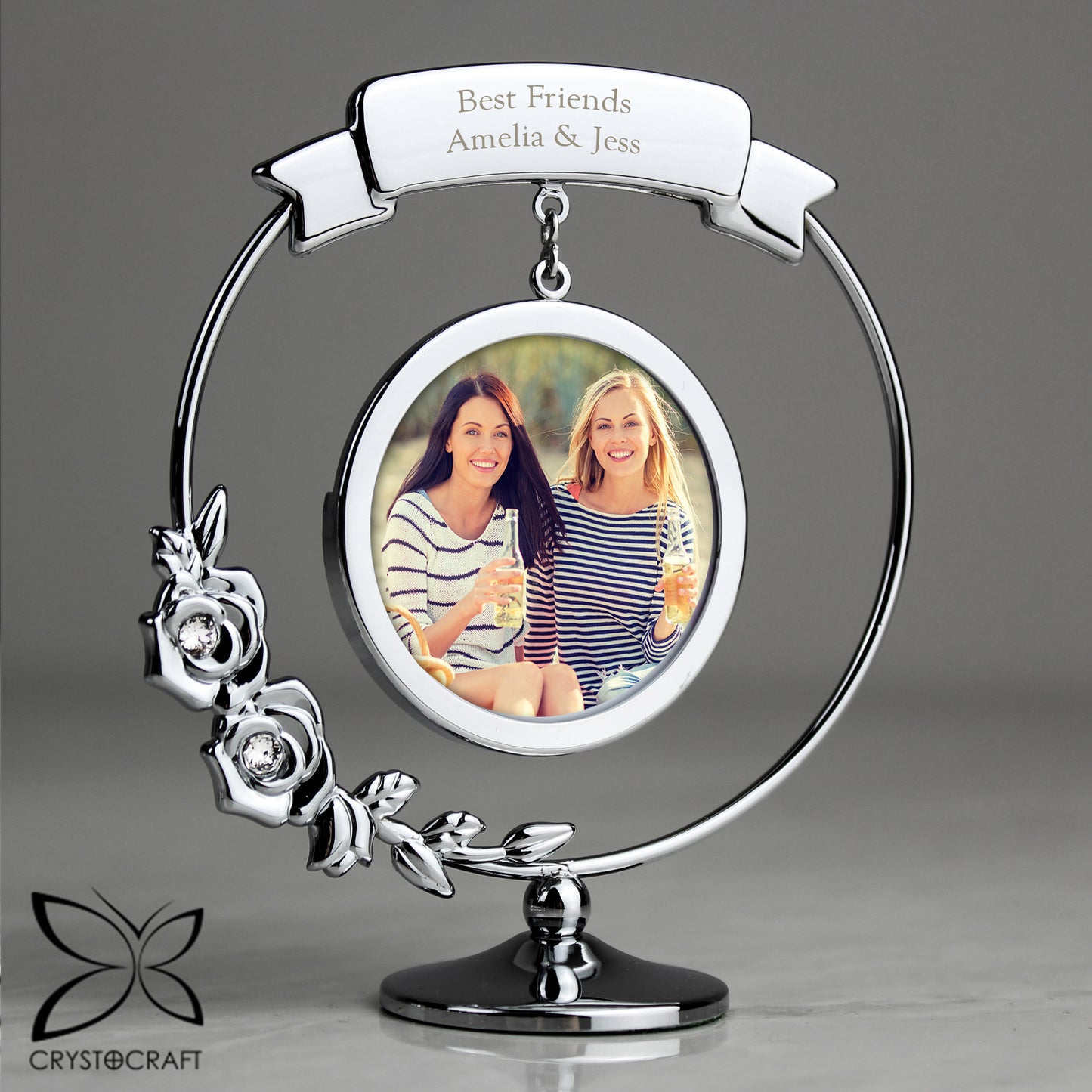 Silver photo frame with a photo of two women and 'Best Friends Amelia & Jess' text, on a grey background.