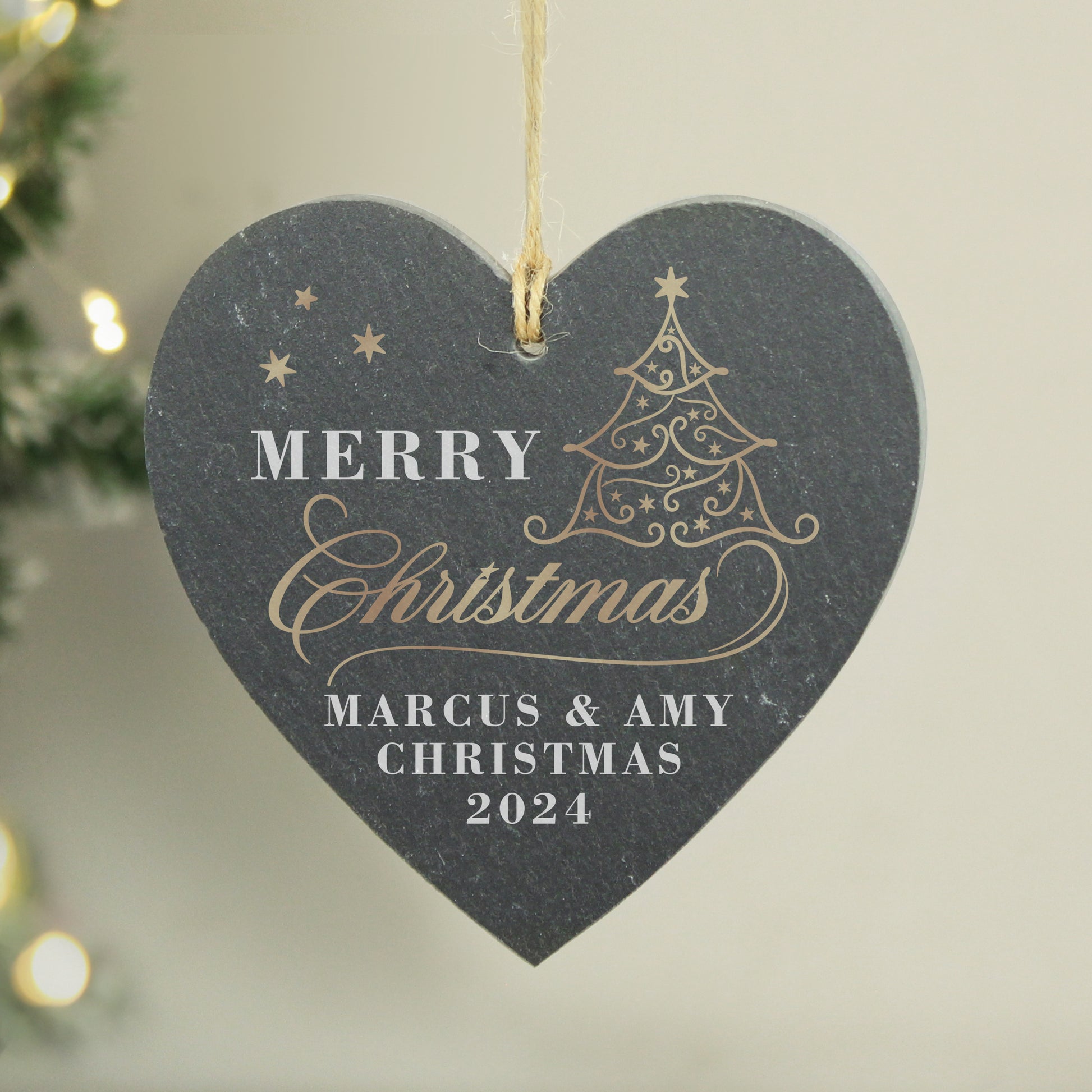 Heart-shaped Christmas ornament with 'Merry Christmas' and personalized text on a neutral background.
